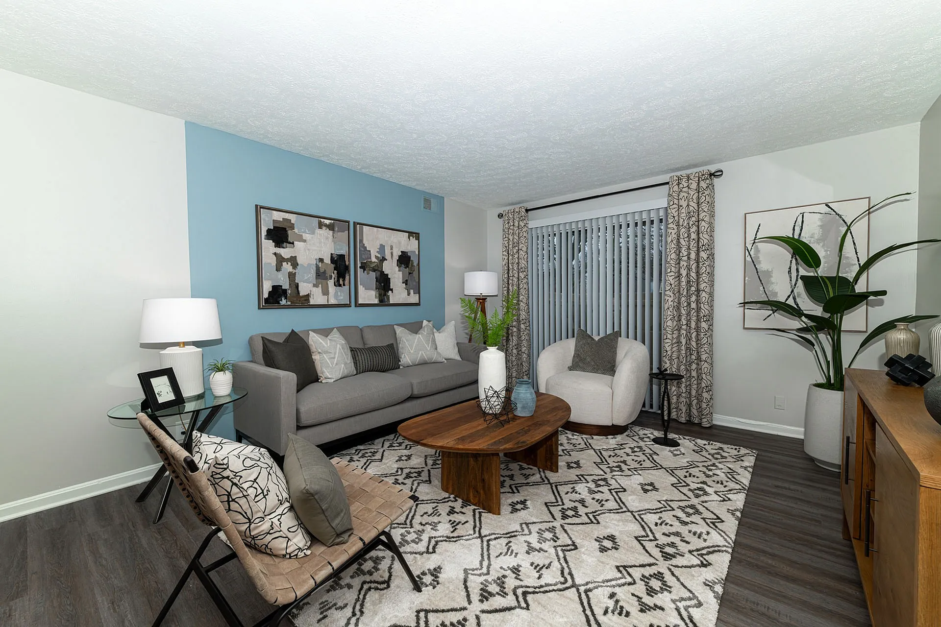 Elegant living room with modern decor, featuring a cozy gray sofa, stylish wood coffee table, and artistic wall art, complemented by a chic blue accent wall.