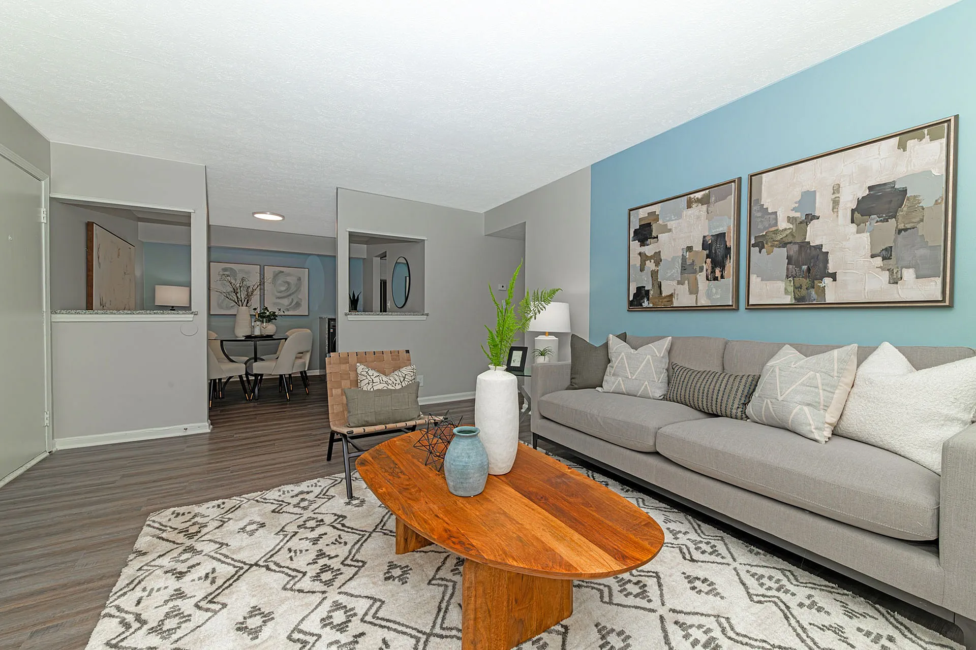 Modern living room with stylish gray sofa, abstract artwork, and chic dining area, highlighting open-concept design and elegant decor.