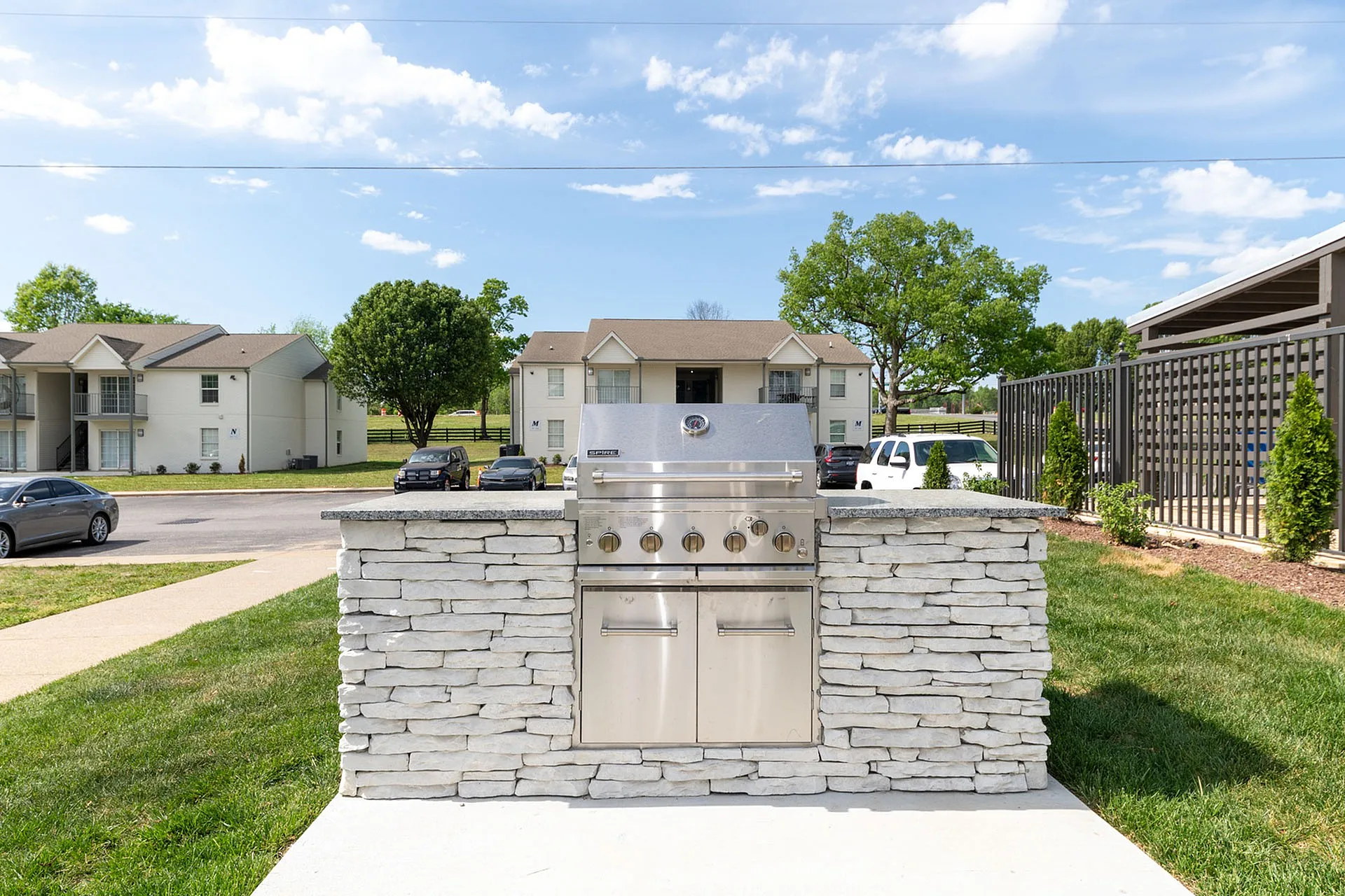 Charming outdoor space featuring a modern stainless steel grill set against stylish stonework, perfect for entertaining and enjoying sunny days.