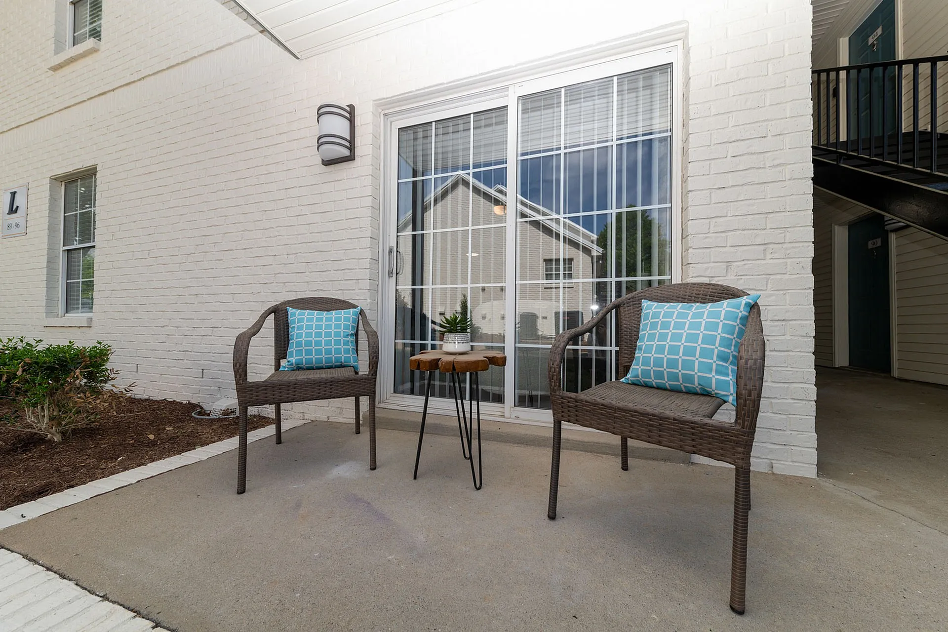 Charming outdoor patio with stylish wicker chairs and vibrant cushions, perfect for cozy relaxation.