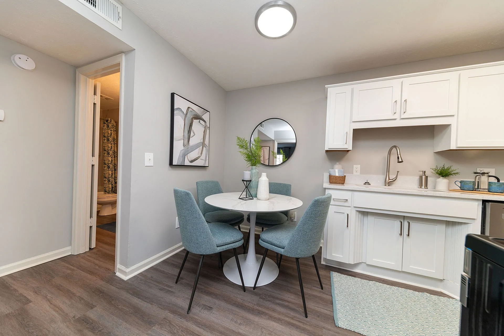 Inviting dining area with modern decor, elegant round table, stylish blue chairs, and a sleek kitchen setup.