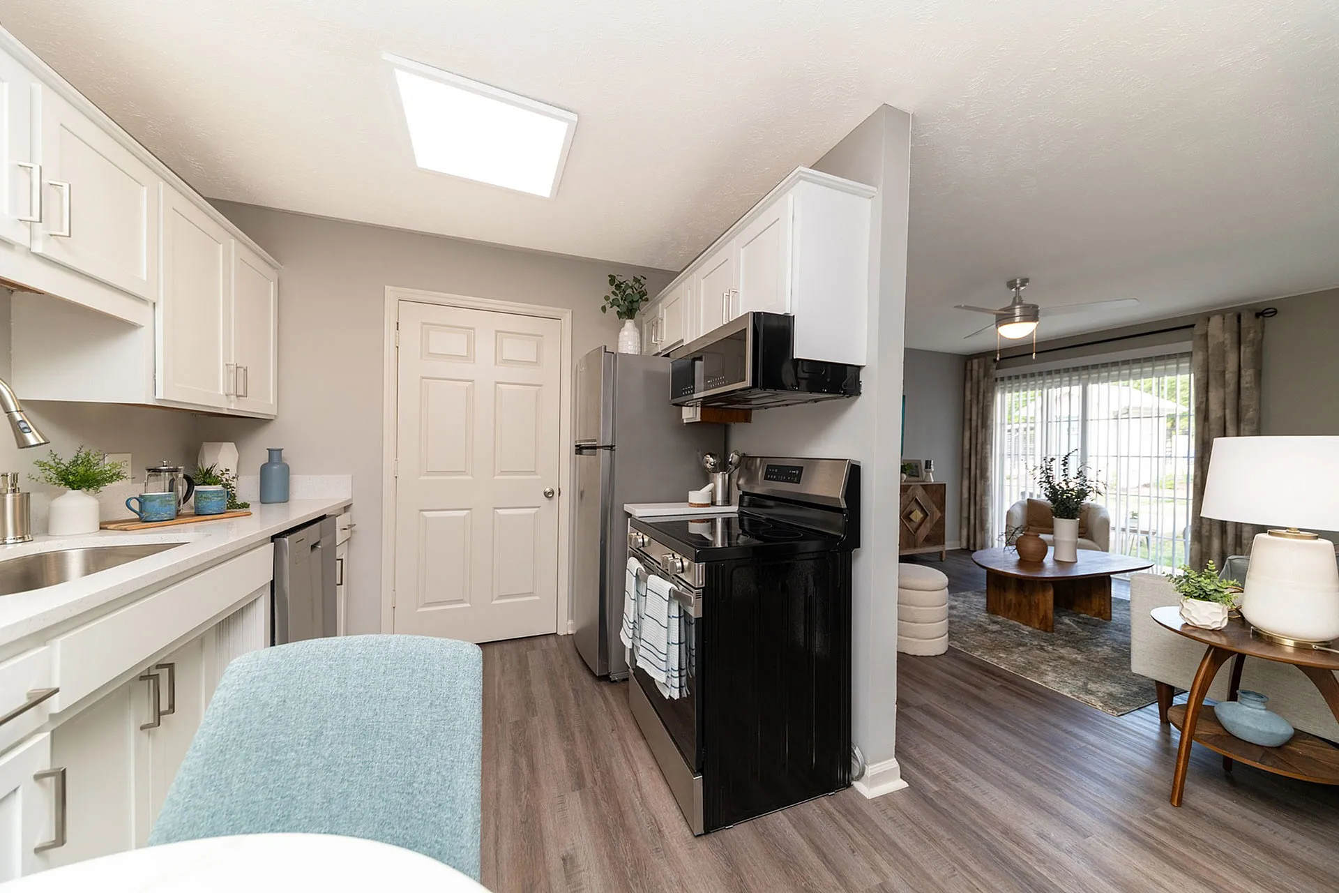 Modern kitchen with elegant cabinetry, sleek appliances, and a cozy living room view featuring stylish decor and natural light.