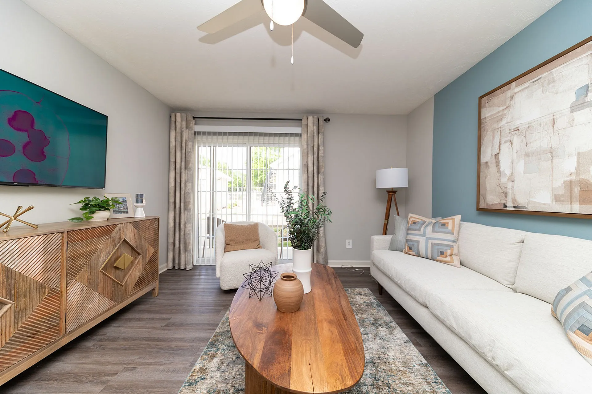 Modern living room with sleek decor, featuring a cozy sofa, elegant wooden coffee table, and contemporary art. Large windows provide abundant natural light.