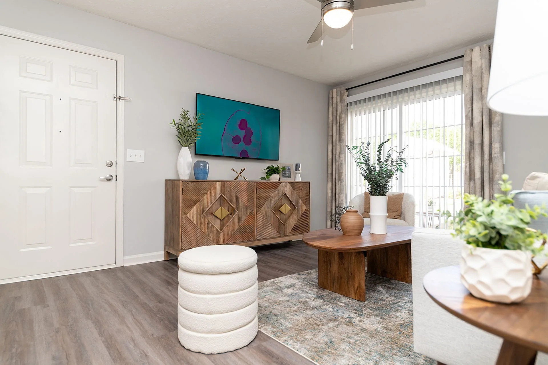Bright and welcoming living room with chic decor, featuring a stylish wooden console, contemporary art piece, and elegant indoor plants.