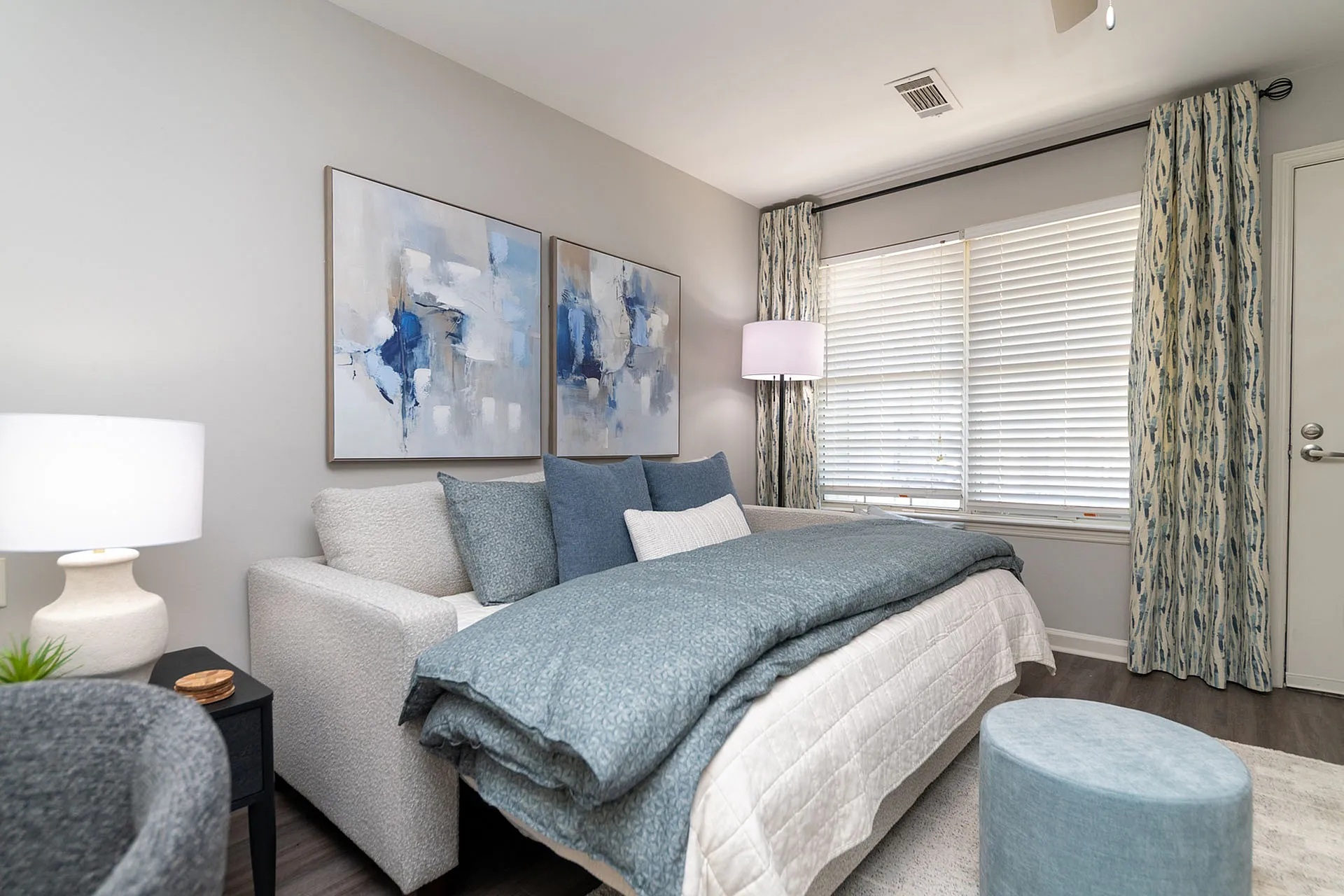 Elegant bedroom with plush bedding, modern artwork, and abundant natural light, perfect for relaxation.