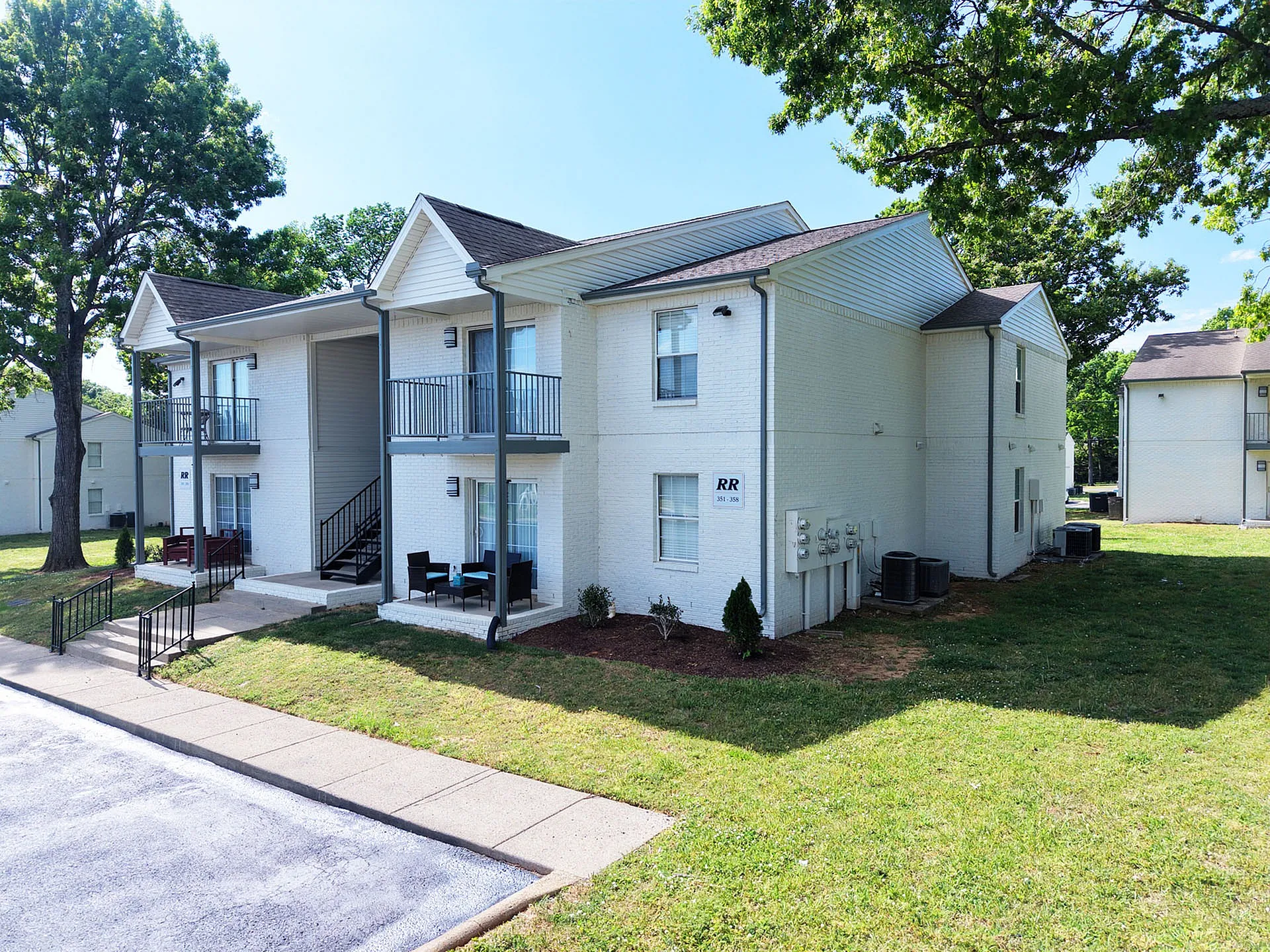 Charming two-story apartment with private balconies and lush green surroundings, offering a serene residential experience.
