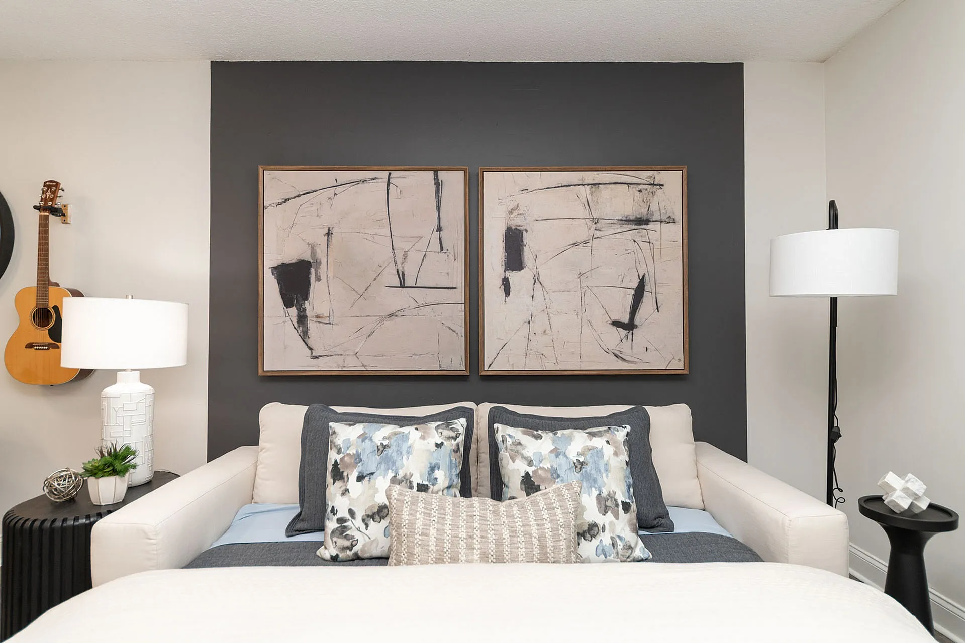 Elegant bedroom featuring modern abstract artwork, cozy pillows, and ambient lighting, creating a serene atmosphere.