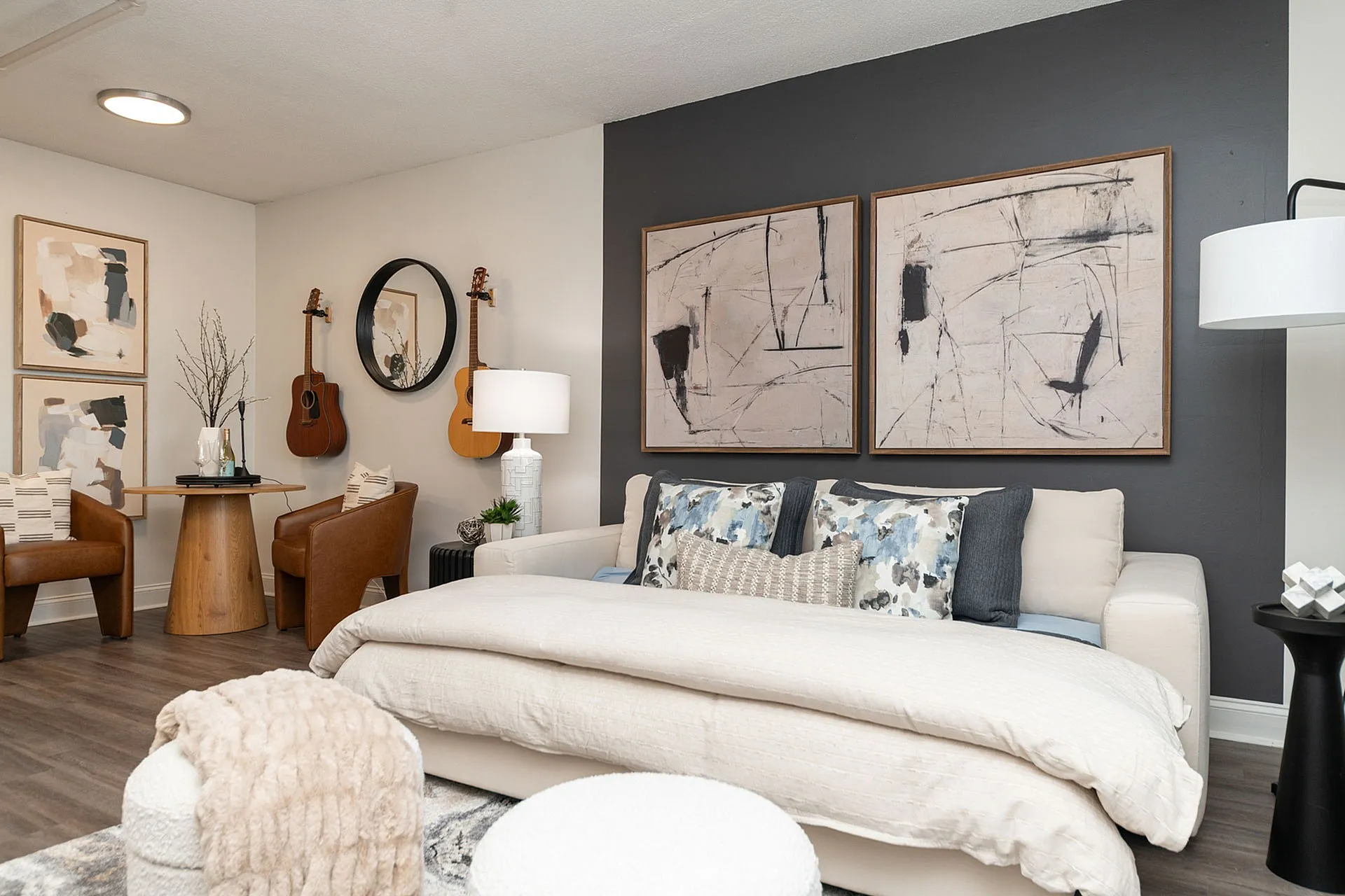 Elegant living room with stylish modern decor, featuring abstract artwork, cozy seating, and guitars adorned on the wall.