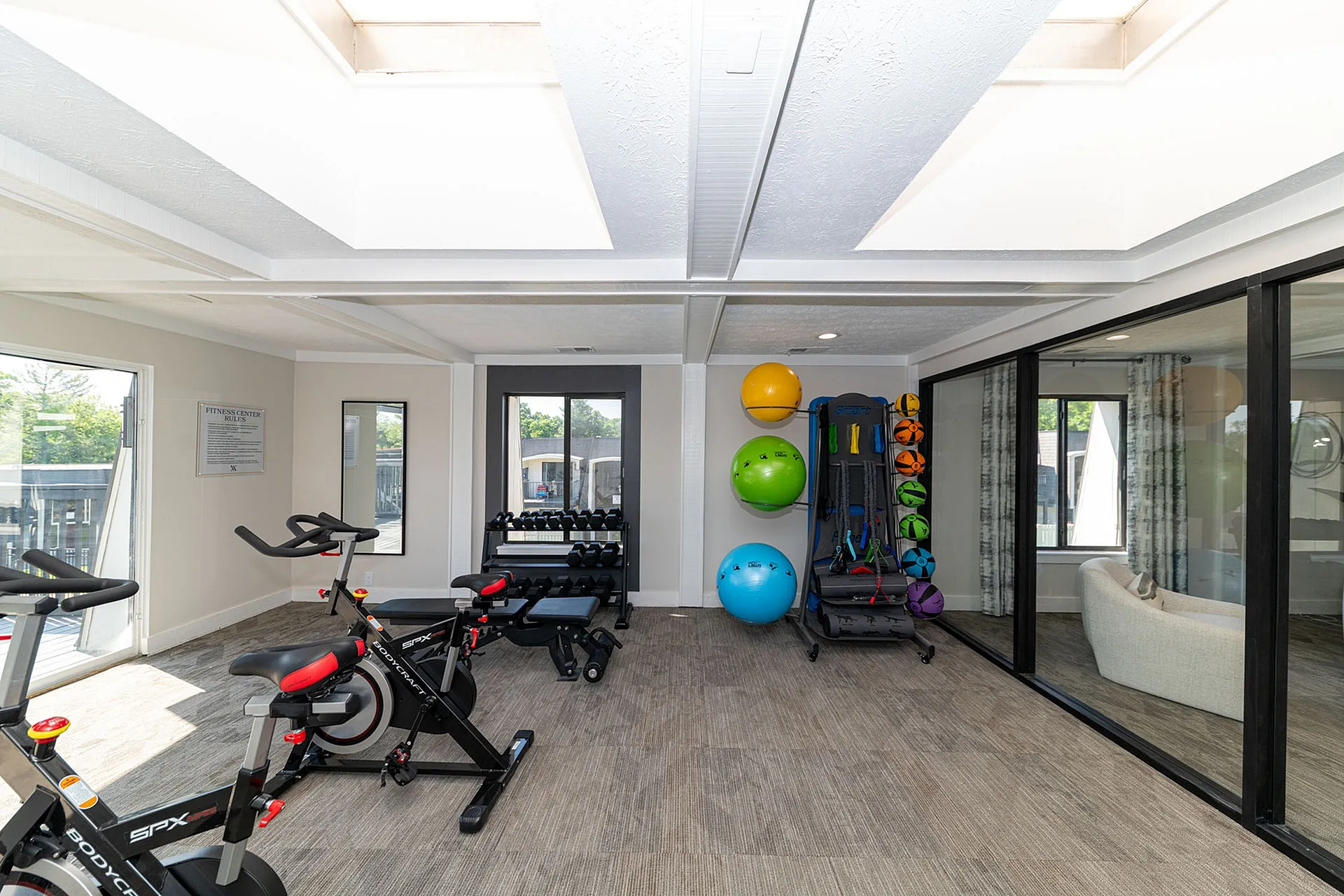Bright and modern fitness center with exercise bikes, dumbbells, and colorful fitness balls, offering a sleek space for workouts.