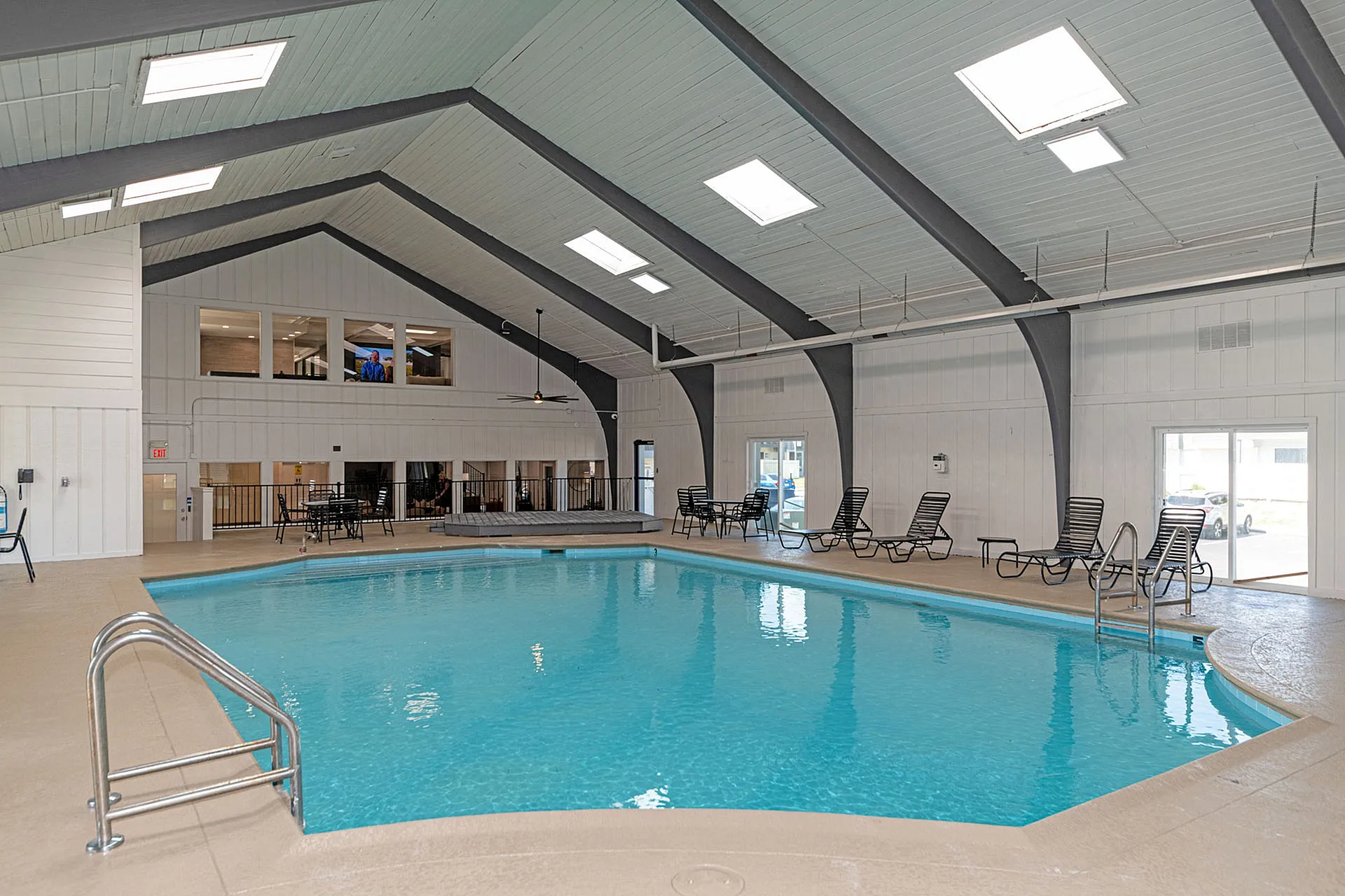 Inviting indoor pool area with skylights, comfortable lounge seating, and modern architecture.
