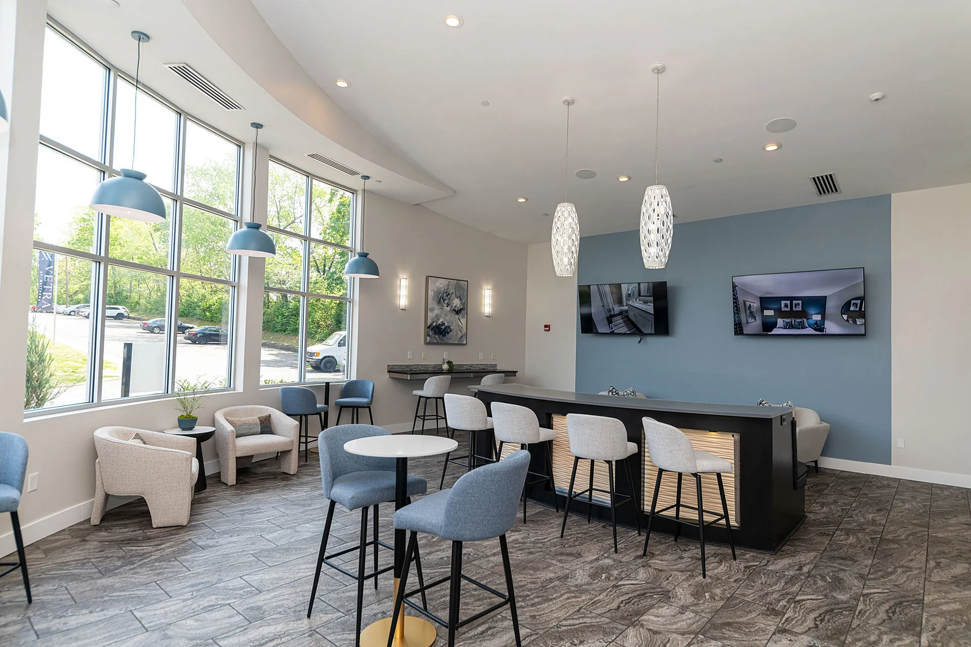 Bright and modern communal area with large windows, stylish pendant lighting, and comfortable seating, perfect for relaxation and social gatherings.
