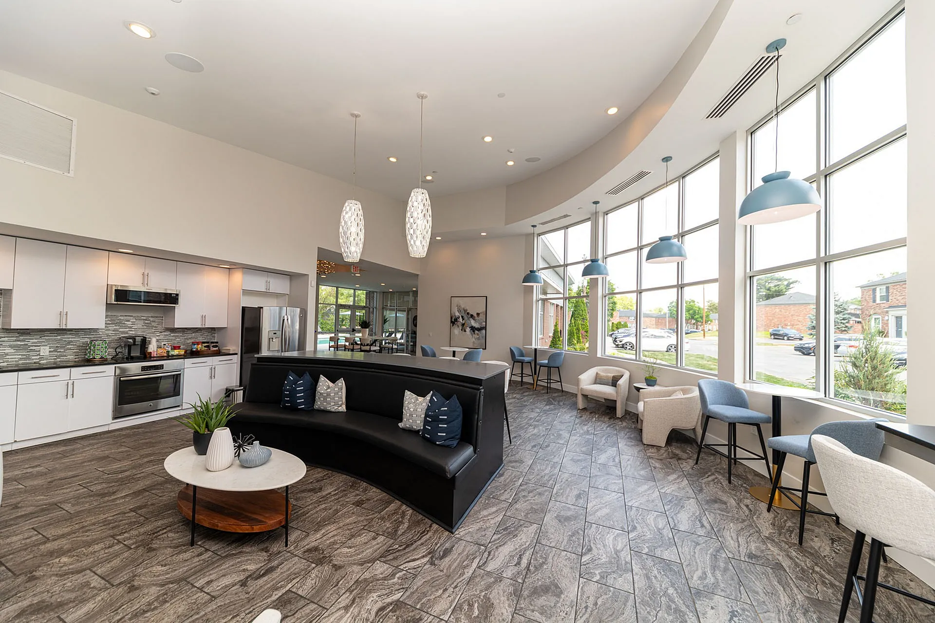 Bright, modern community space with sleek kitchen, stylish seating, and large windows providing ample natural light and outdoor views.