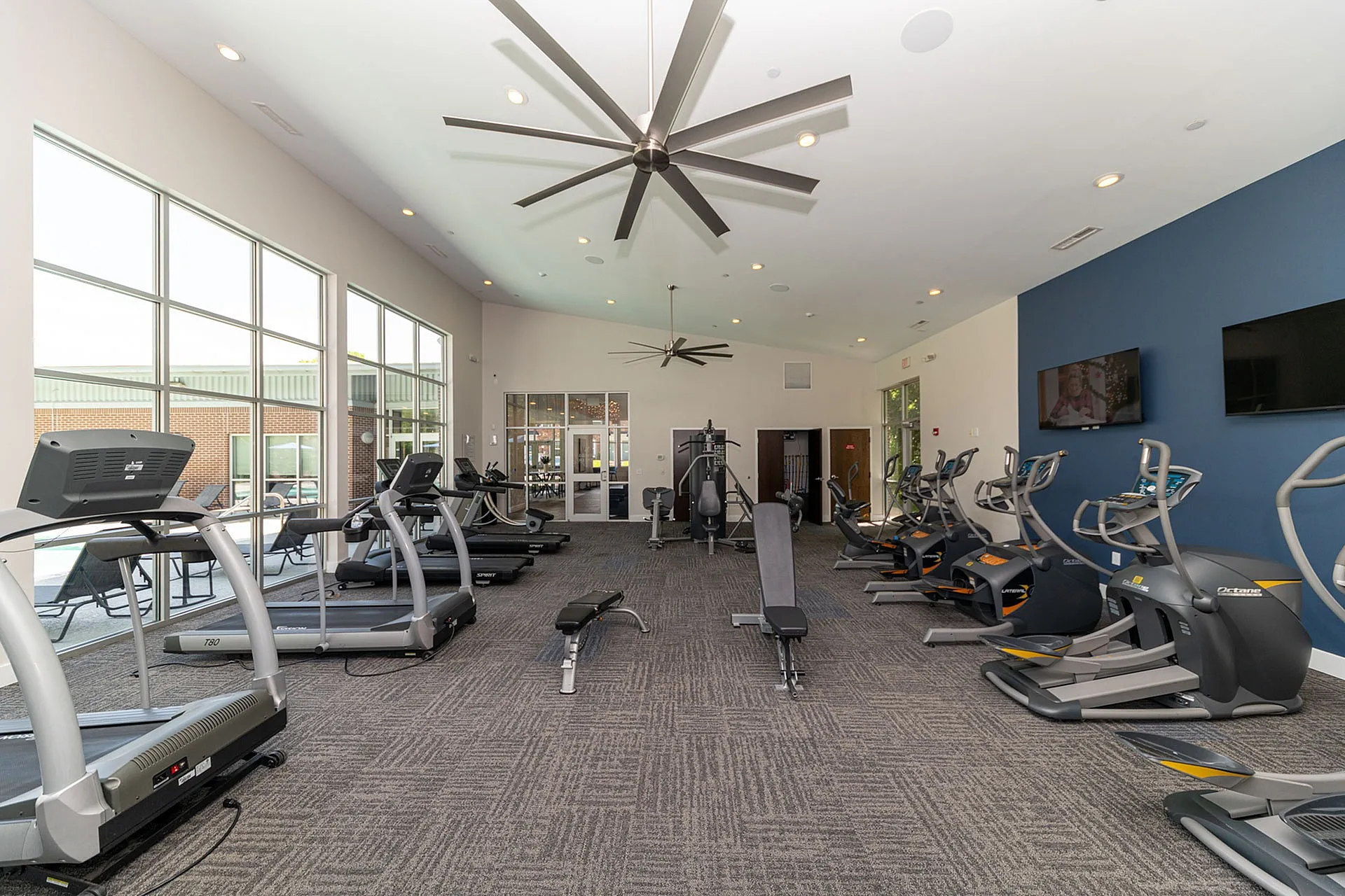 Modern fitness center with state-of-the-art equipment and large windows offering natural light.