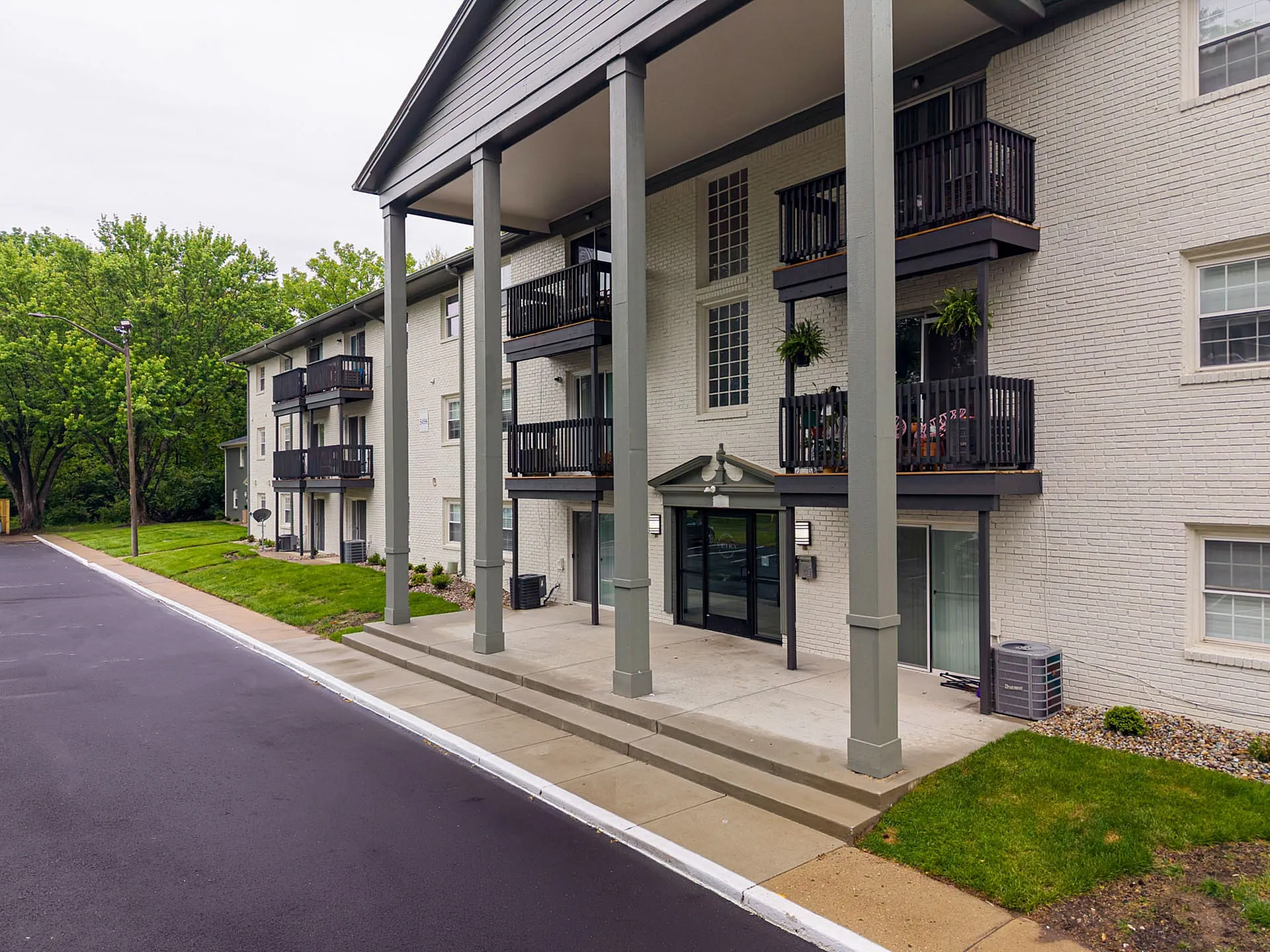 Modern apartment exterior with elegant balconies and lush greenery, offering a stylish and inviting living space.