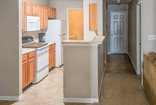 Inviting kitchen and hallway in a cozy apartment featuring warm wood cabinetry, modern appliances, and elegant tiling.