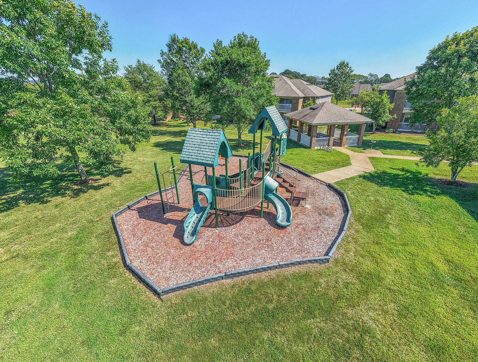 Vibrant apartment community playground nestled in lush green surroundings, perfect for family fun and outdoor relaxation.