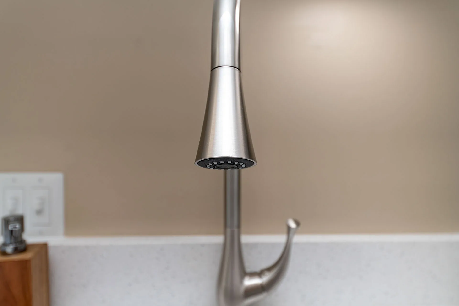 Elegant, sleek kitchen faucet with modern stainless steel design over polished countertop.