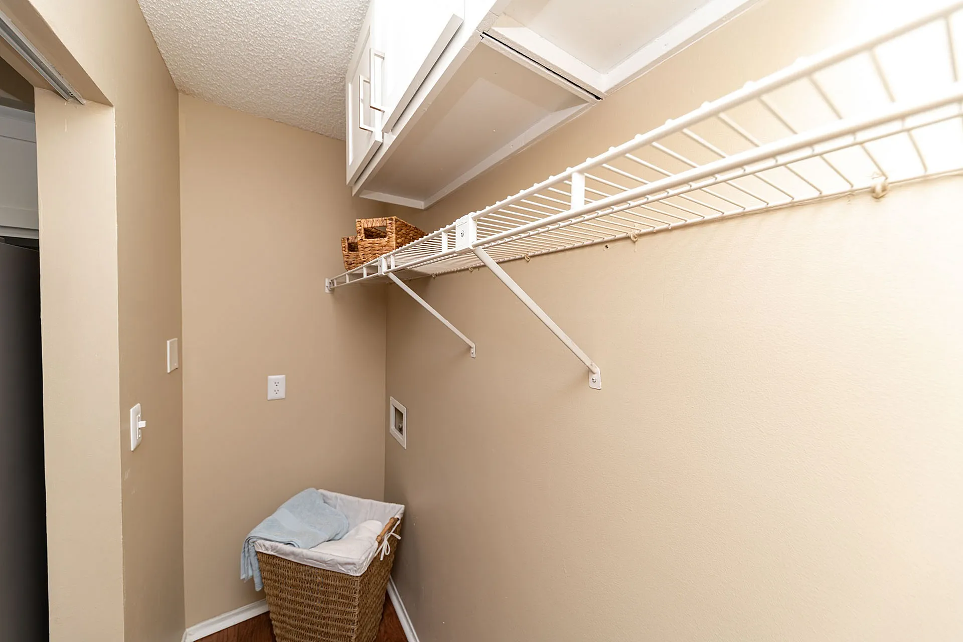 Spacious laundry room with ample storage featuring modern wire shelving and elegant wicker baskets.