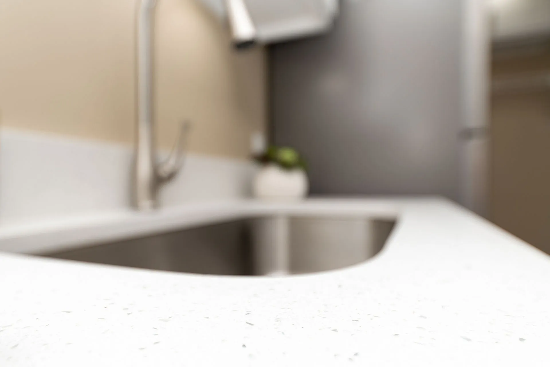 Sleek modern kitchen with elegant white countertop and stainless steel sink, offering a stylish and functional space.