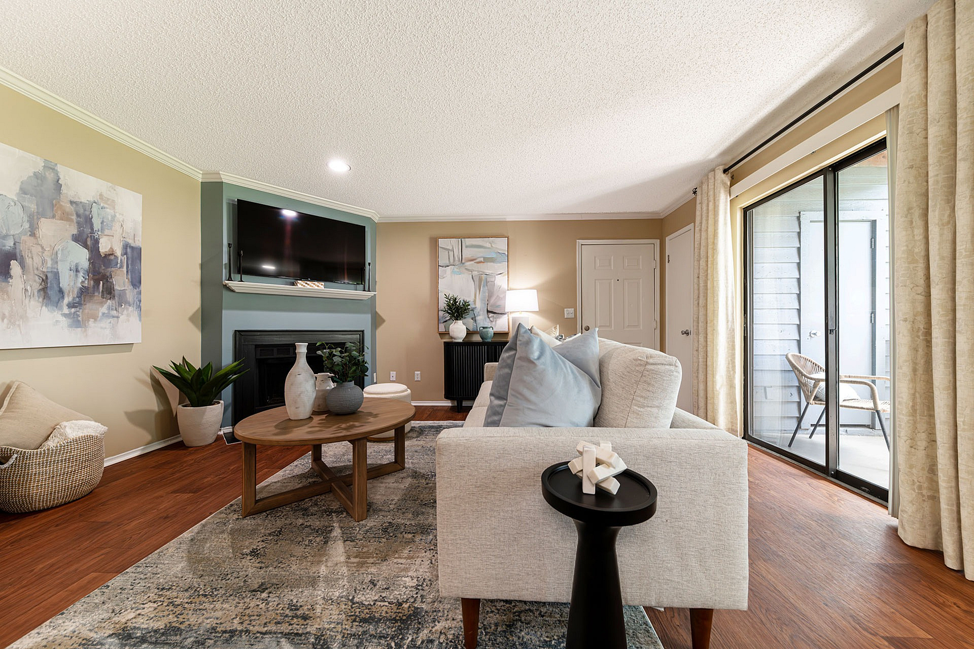 Inviting living room with contemporary decor, featuring a comfy sofa, elegant coffee table, and a flat-screen TV above a modern fireplace, accented by plush cushions and a warm ambiance from natural lighting through large sliding doors.