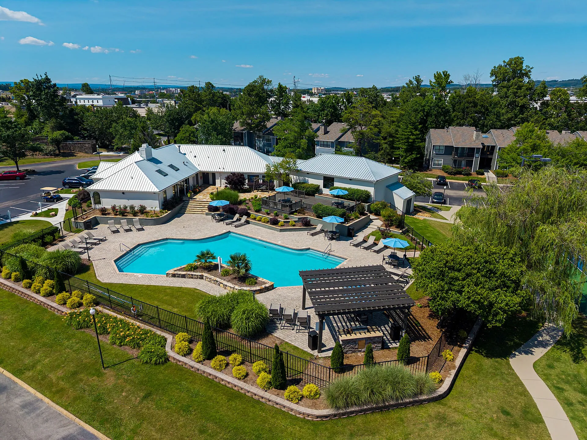 Charming apartment complex with a stunning outdoor pool, lush landscaping, and cozy seating areas, perfect for relaxation and social gatherings.