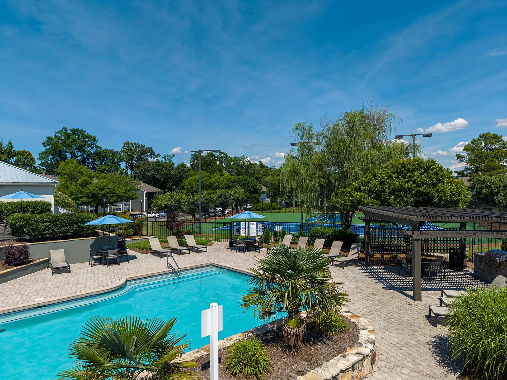Inviting outdoor area with a sparkling pool, comfortable lounge chairs, and a charming pergola, perfect for relaxation amid lush greenery.