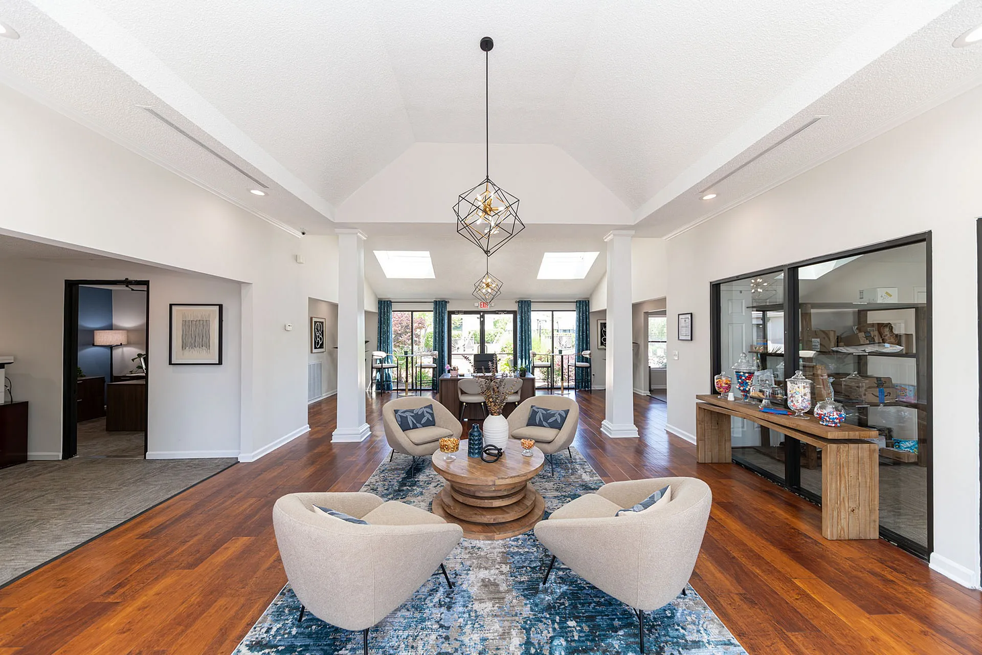 Elegant office lobby with modern decor, featuring stylish seating, a large rug, and natural light pouring in through skylights.