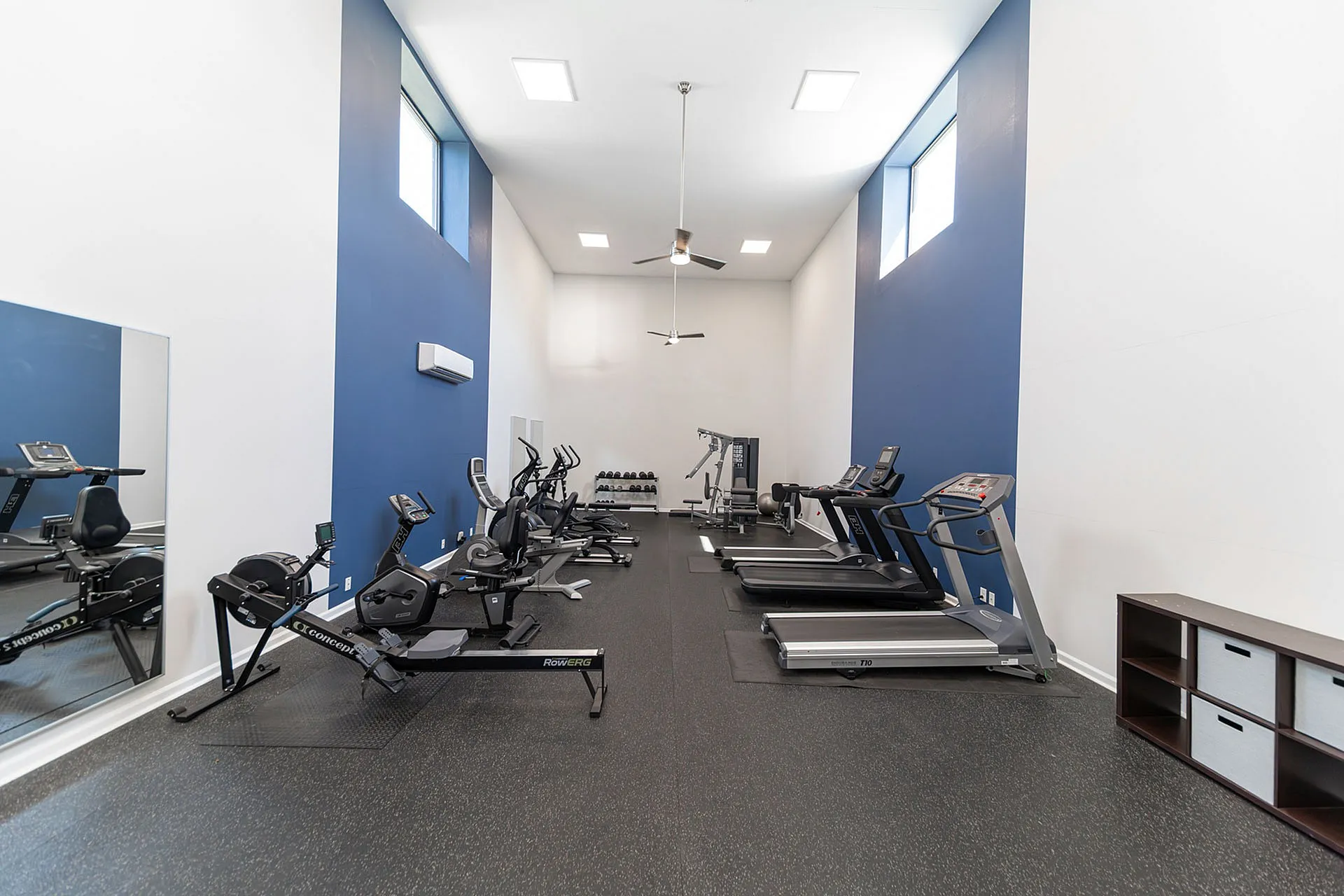 Modern fitness center with state-of-the-art exercise equipment, sleek treadmill machines, and vibrant blue accent walls.