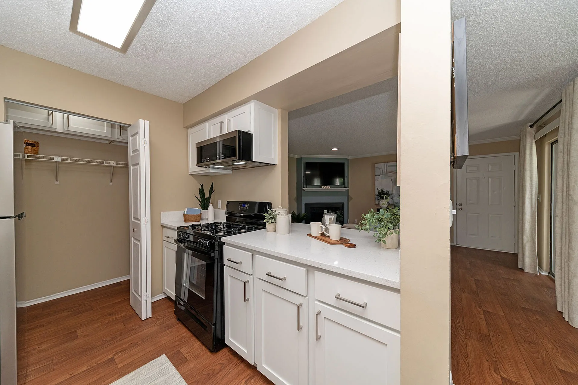 Chic open-concept kitchen with modern appliances, sleek white cabinetry, and a cozy view into the living area.