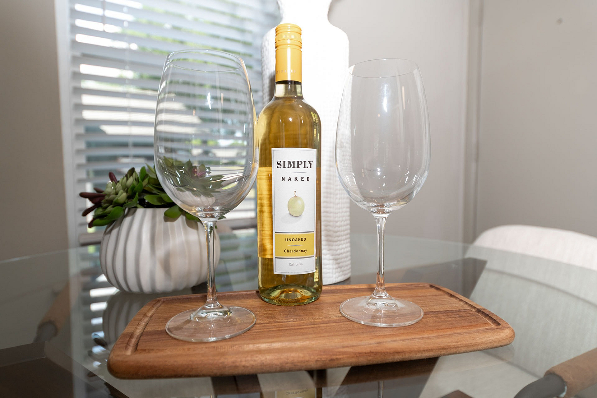 Elegant dining setup featuring a bottle of Chardonnay with two wine glasses on a wooden tray, enhancing the cozy ambiance of the stylish apartment.