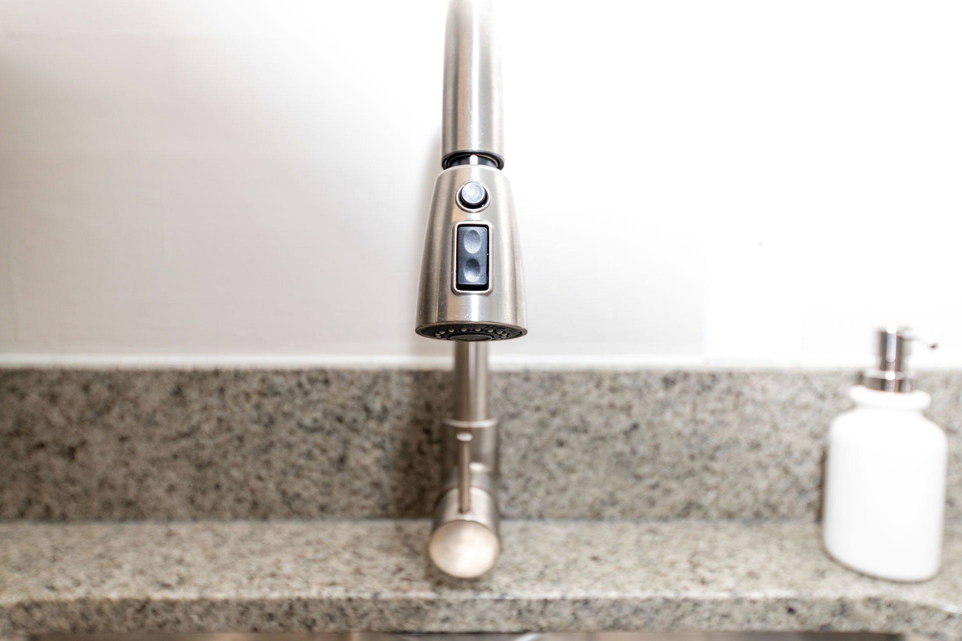 Modern kitchen faucet with sleek stainless steel design against elegant granite countertop.