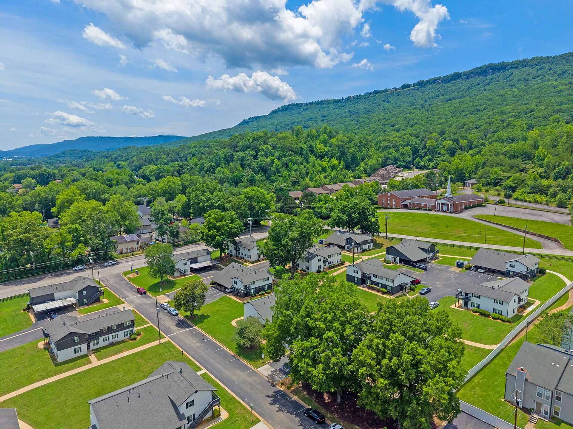 Charming residential community nestled in lush greenery with picturesque mountain views, featuring modern homes and scenic surroundings.