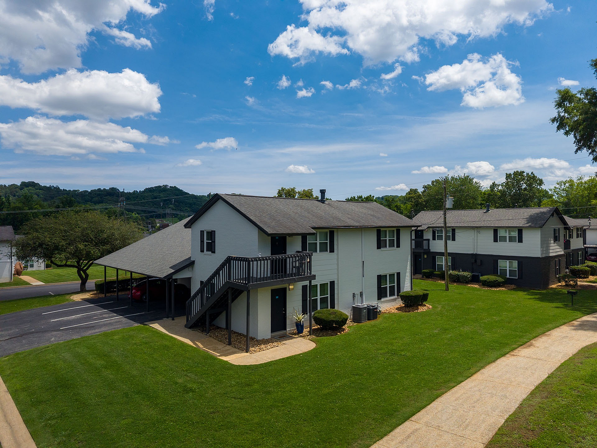 Charming apartment building surrounded by lush green lawns and a clear blue sky, offering serene suburban living.