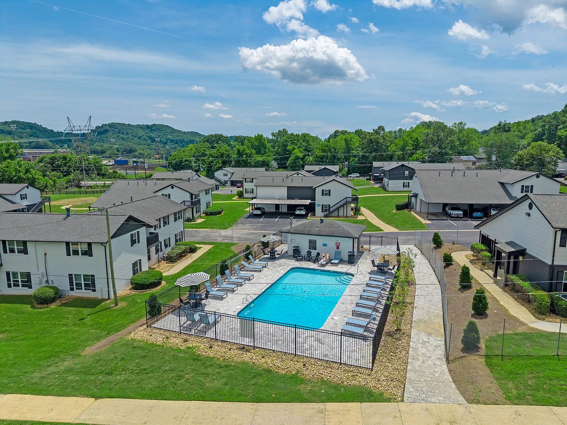 Charming residential community with a sparkling outdoor pool, surrounded by lush greenery and inviting walkways.