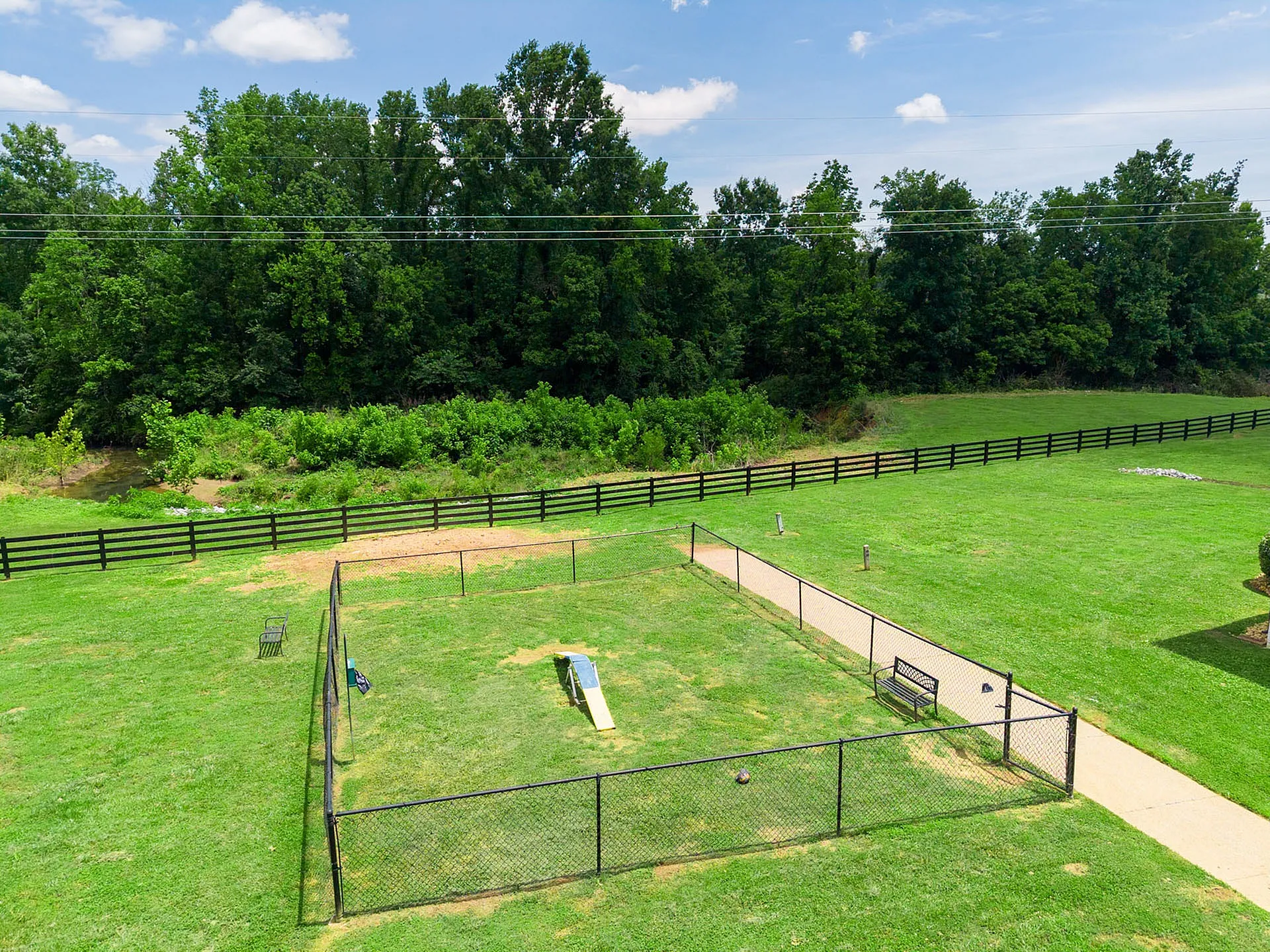 Welcoming green space with fenced dog park and lush trees, offering tranquility and outdoor enjoyment.