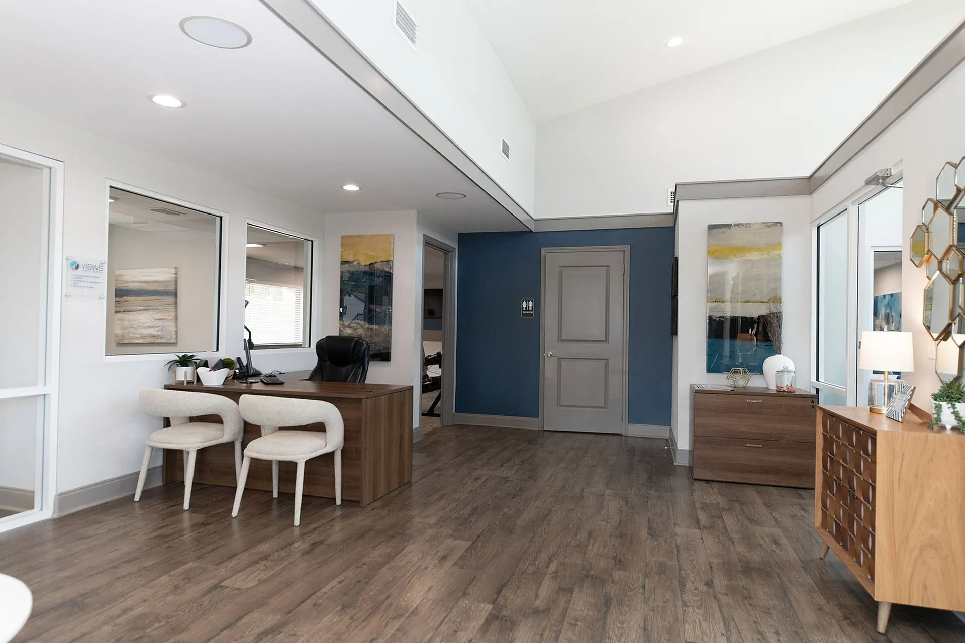 Modern office space with stylish decor, featuring hardwood floors, elegant furniture, and contemporary artwork on the walls.