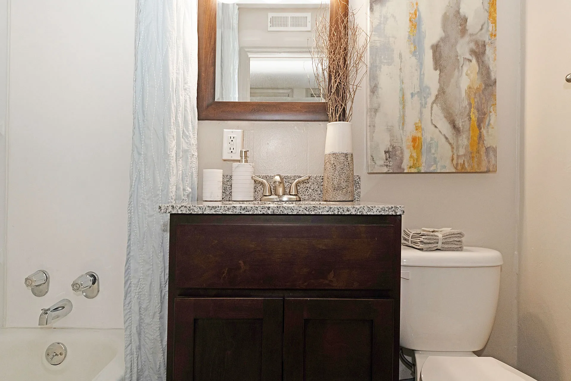 Modern bathroom featuring a sleek vanity with granite countertop, elegant mirror, and contemporary artwork for a stylish touch.