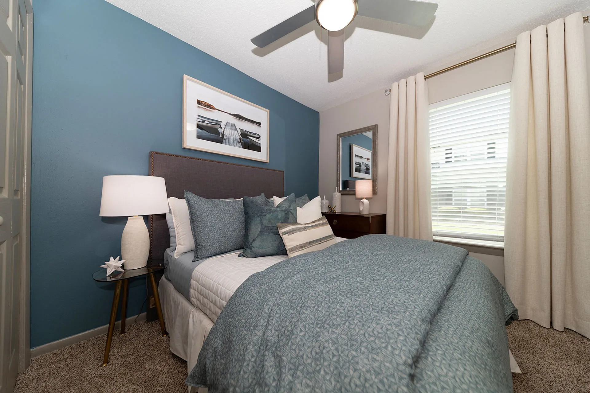 Inviting bedroom with elegant blue accent wall, cozy bedding, and stylish decor.