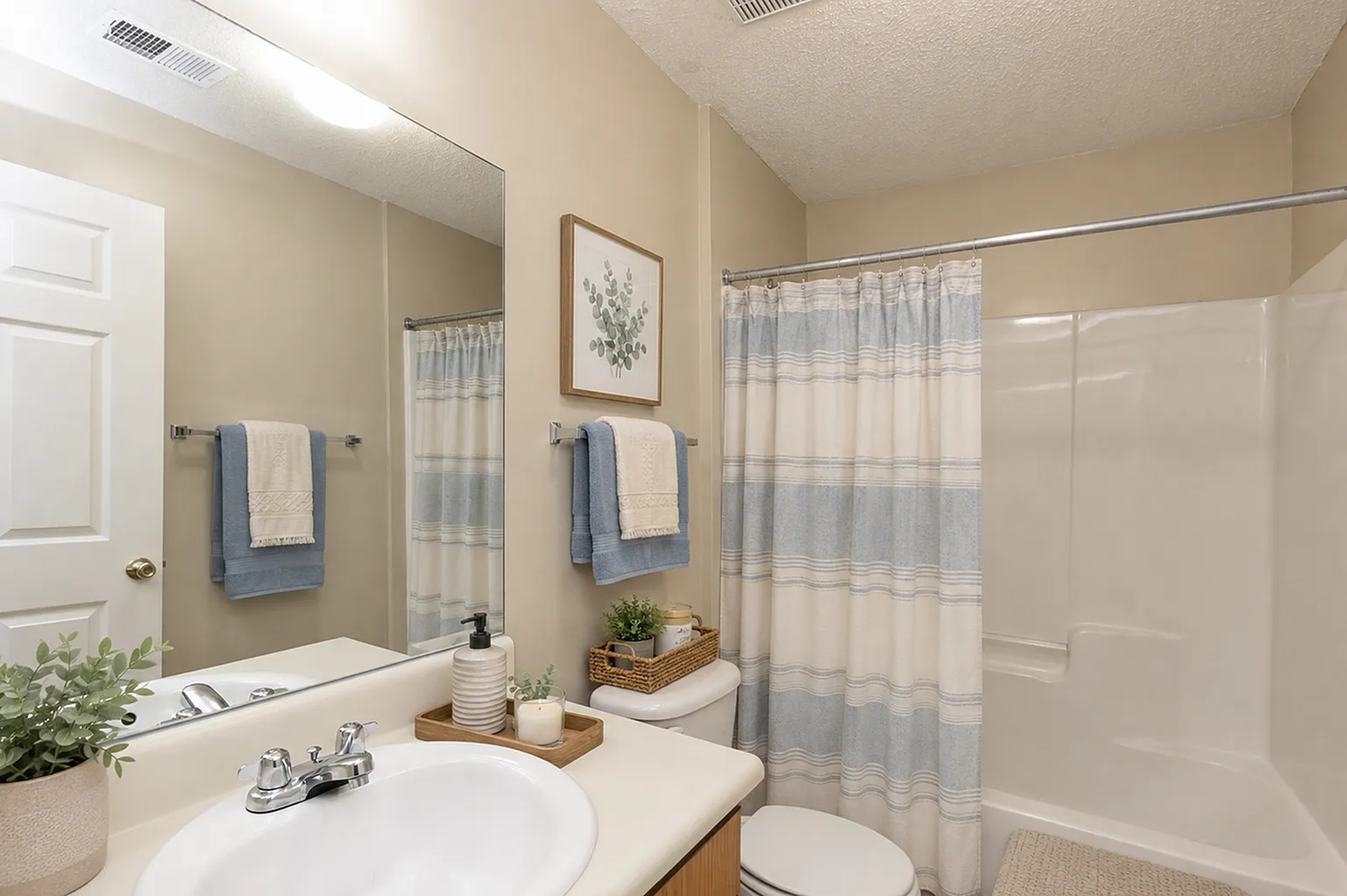 Inviting bathroom with elegant decor, featuring a sleek sink, cozy shower area, and tasteful greenery accents.