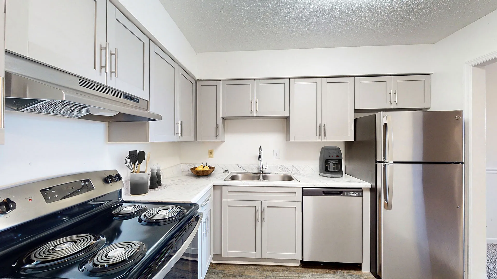 Contemporary kitchen with sleek stainless steel appliances, elegant white cabinetry, and marble countertops.