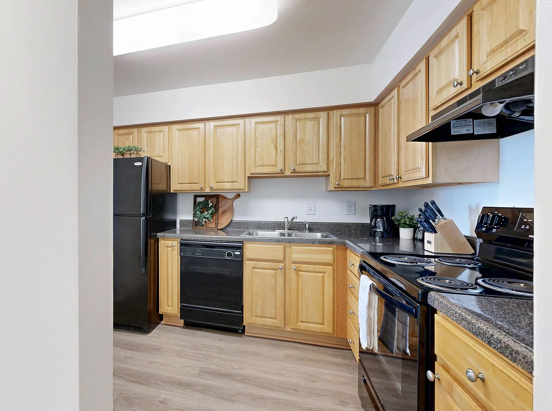 Charming kitchen with modern black appliances, light wood cabinetry, and elegant countertops.