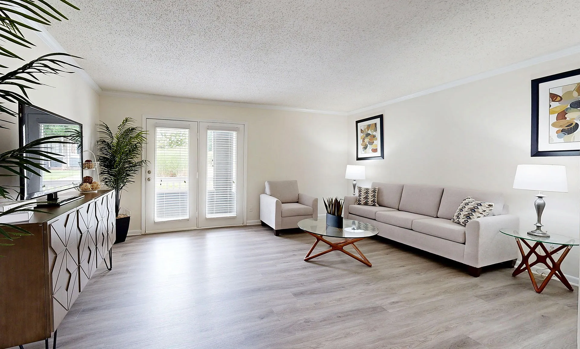 Bright and inviting living room with modern decor, featuring sleek hardwood floors, elegant furniture, and abundant natural light from French doors.