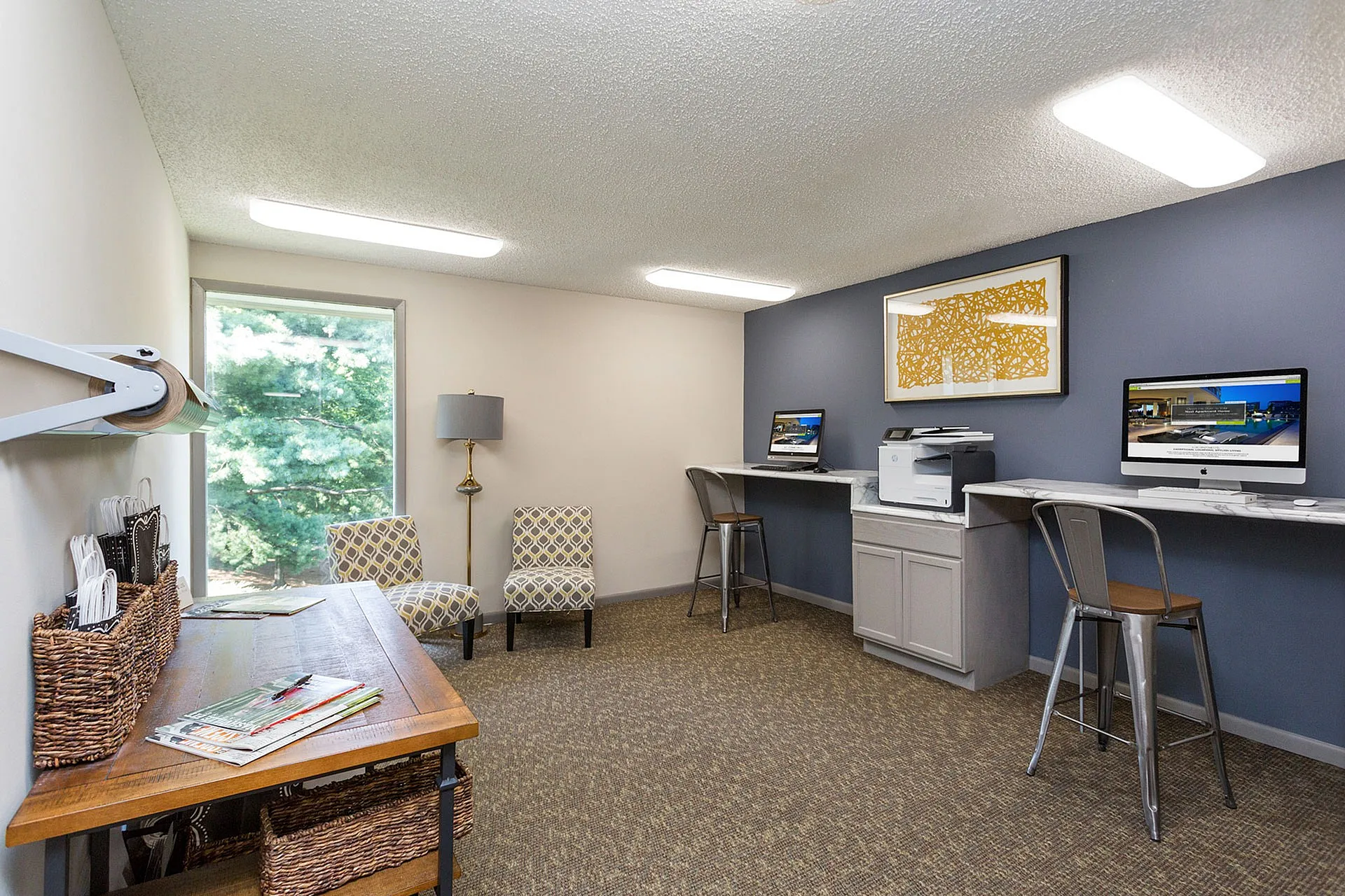 Chic home office with stylish seating, abundant natural light, and dual computer stations for a productive workspace.
