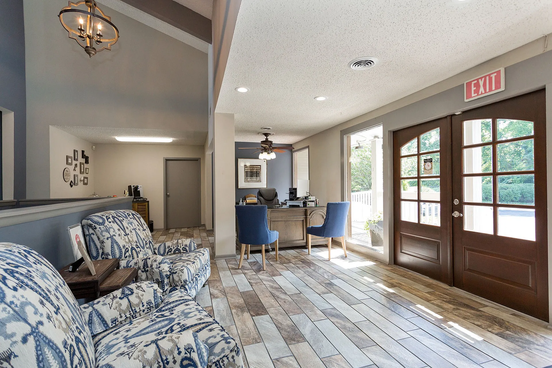 Inviting lobby with elegant patterned armchairs, wooden flooring, and abundant natural light through large windows.
