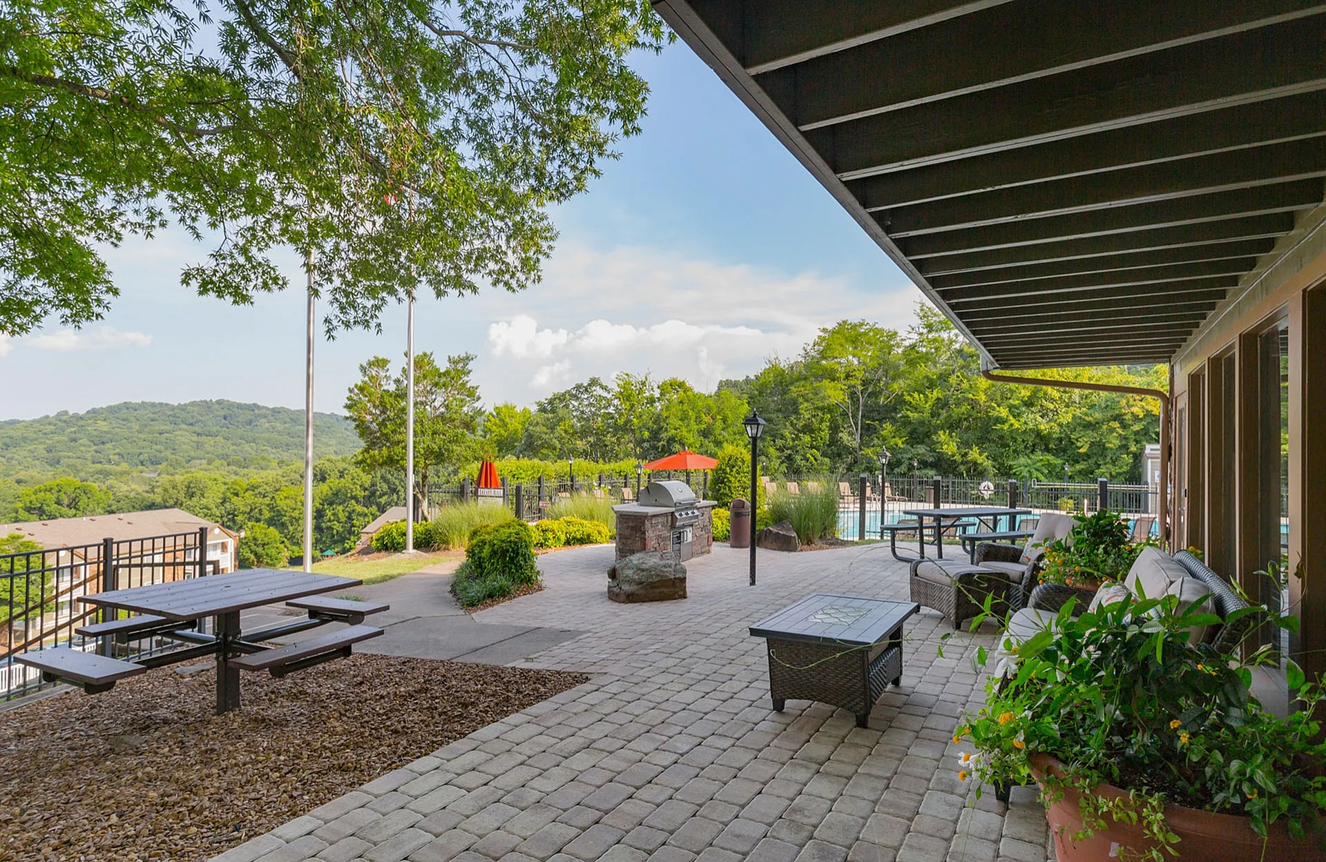 Charming outdoor patio with scenic views, featuring a barbecue grill, stylish seating, and lush greenery, perfect for relaxing in a serene environment.