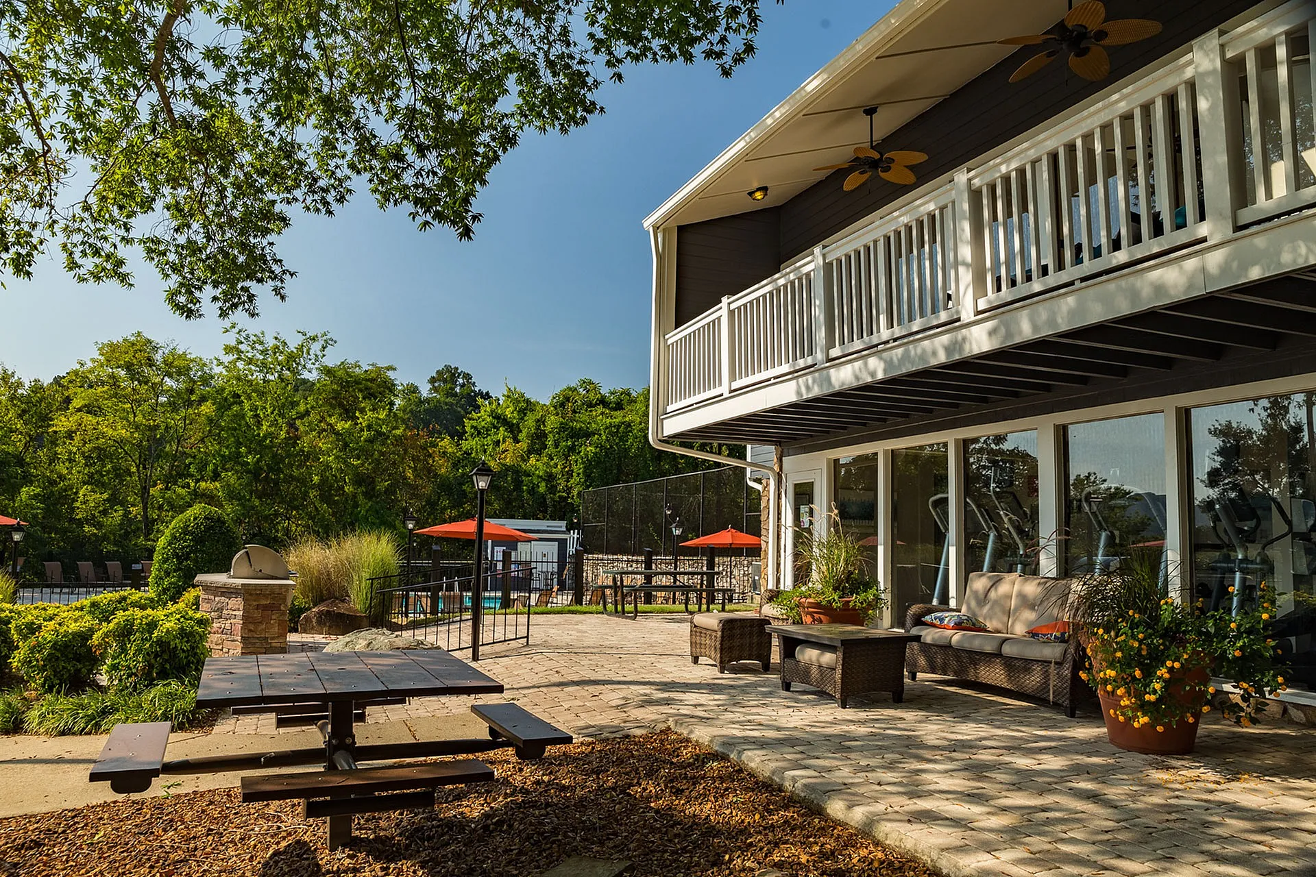 Inviting outdoor patio area with lush greenery, modern seating, BBQ grill, and charming picnic spot perfect for relaxation.