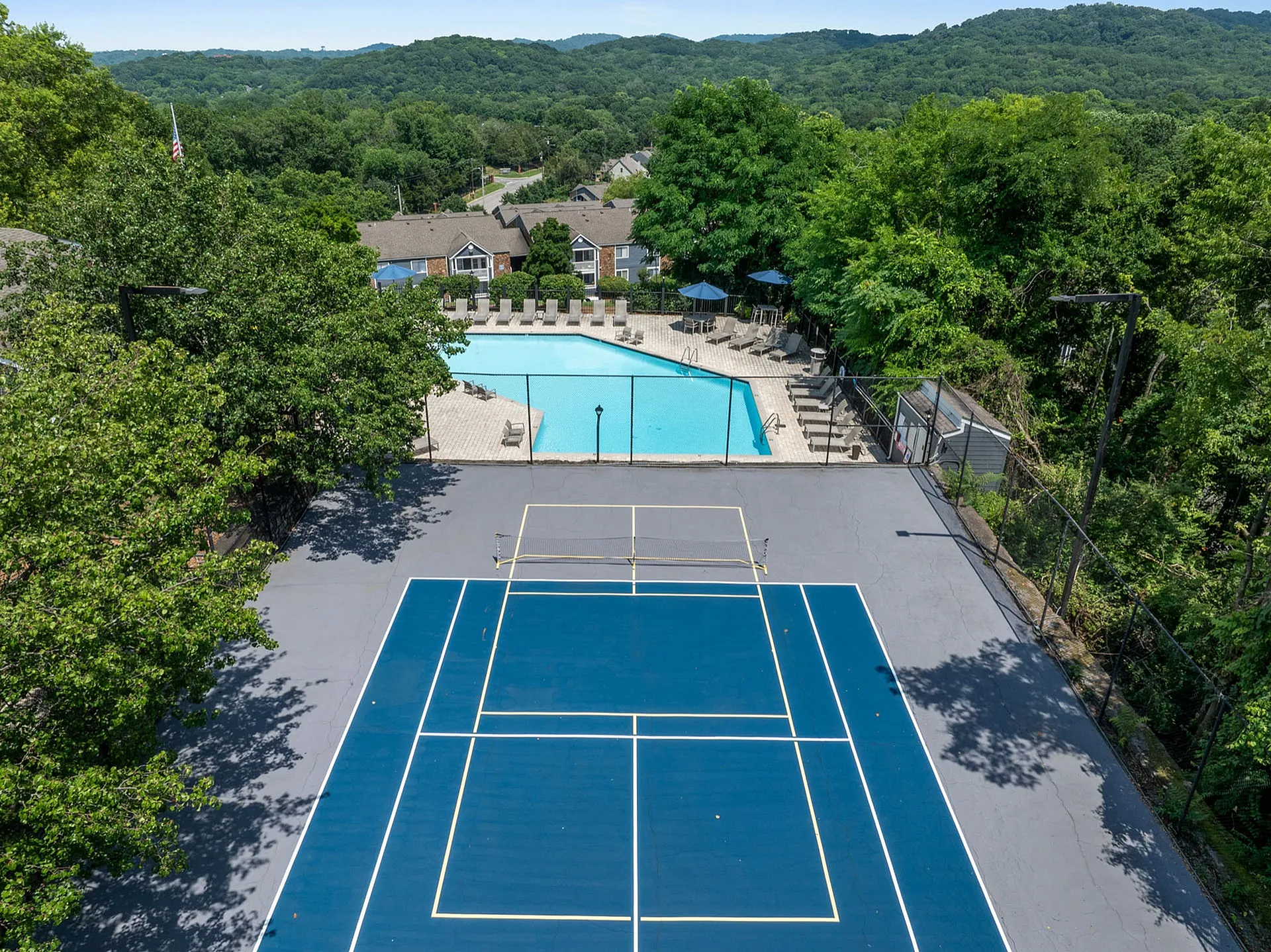 Scenic outdoor amenities featuring a vibrant tennis court and inviting pool surrounded by lush green landscape.