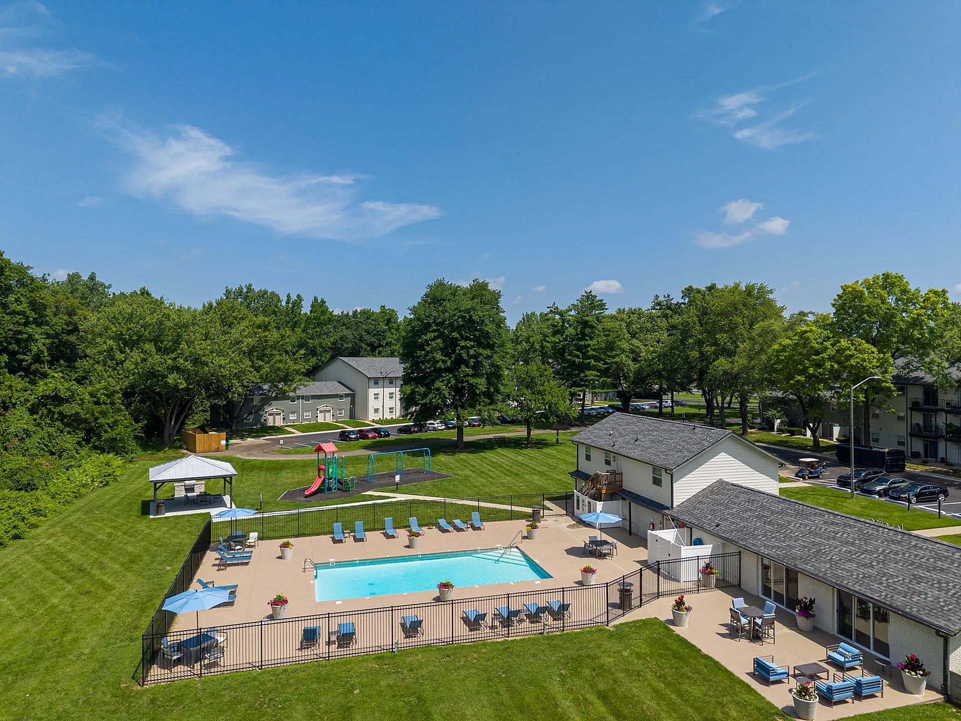 Charming community view with a refreshing swimming pool, vibrant playground, and lush green surroundings.