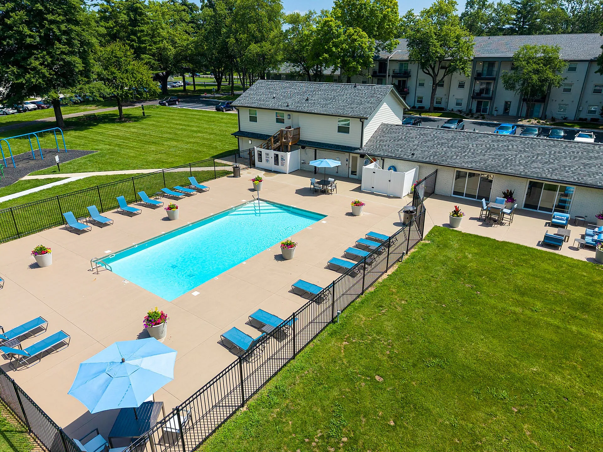 Inviting outdoor pool area with modern loungers, umbrellas, and lush surrounding greenery in a vibrant residential community.
