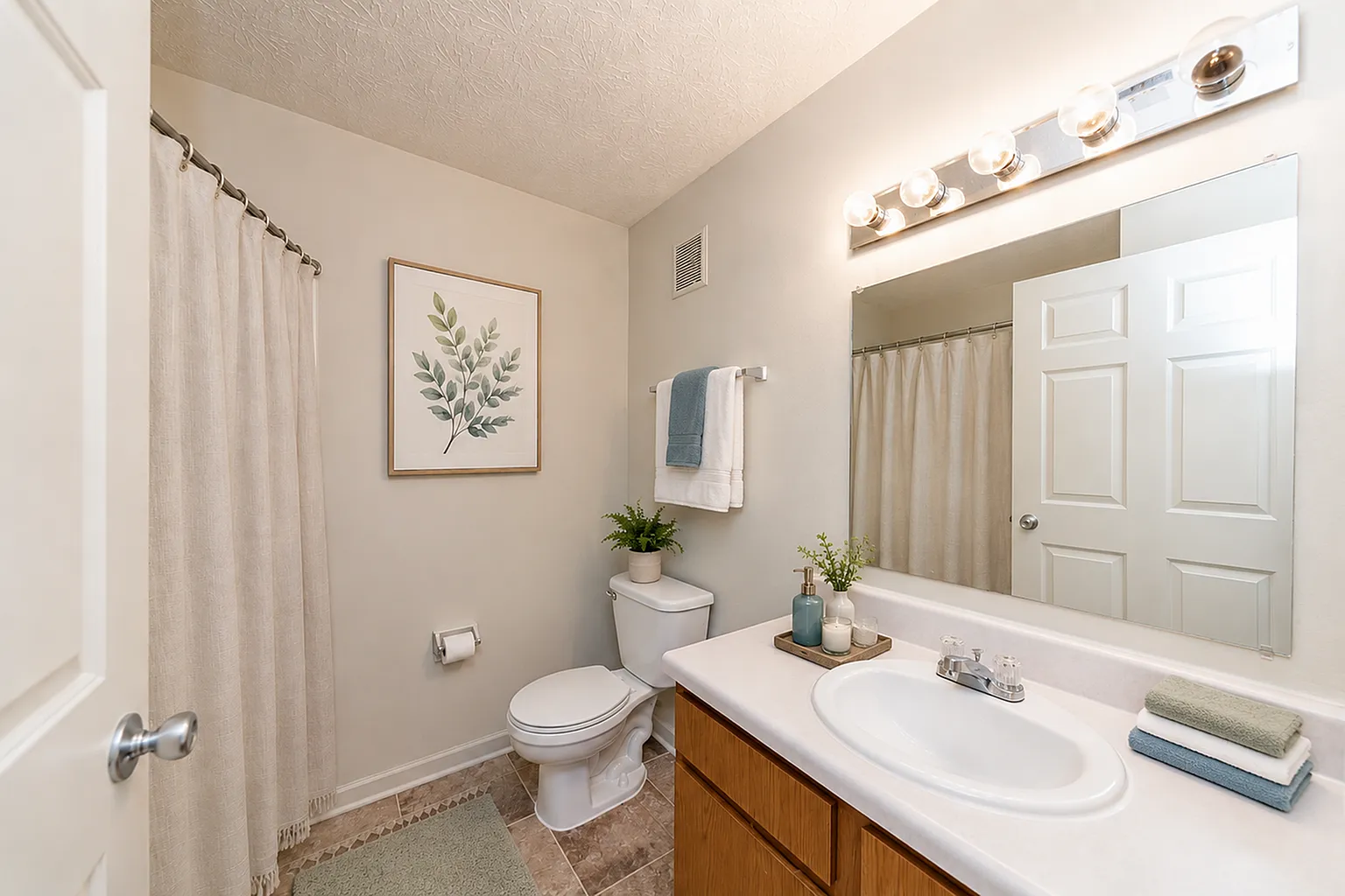 Inviting bathroom featuring sleek fixtures, a large mirror, and tasteful decor with a potted plant and elegant wall art.